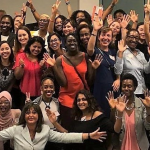 Photo of about 35 members of the Immigrant Women in Business (IWB) at an event. Founder Svetlana Ratnikova in the centre with outstretched hands. Photo provided.