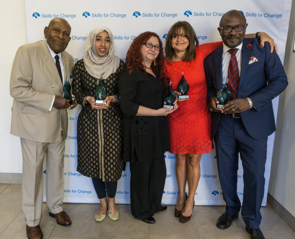 Image of five people standing against a backdrop. Svetlana is holding an award and stands in the middle.
