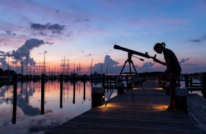 An image of a girl looking through a telescope at the night sky