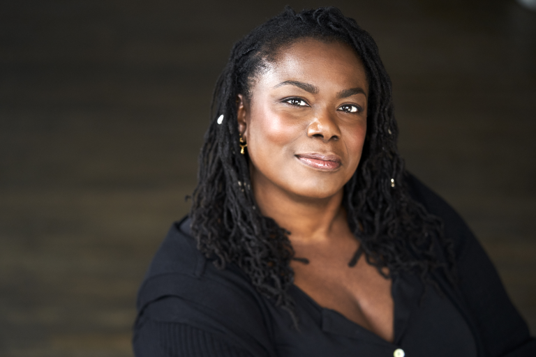 Head shot of a black woman with long black braids, wearing blue shirt.